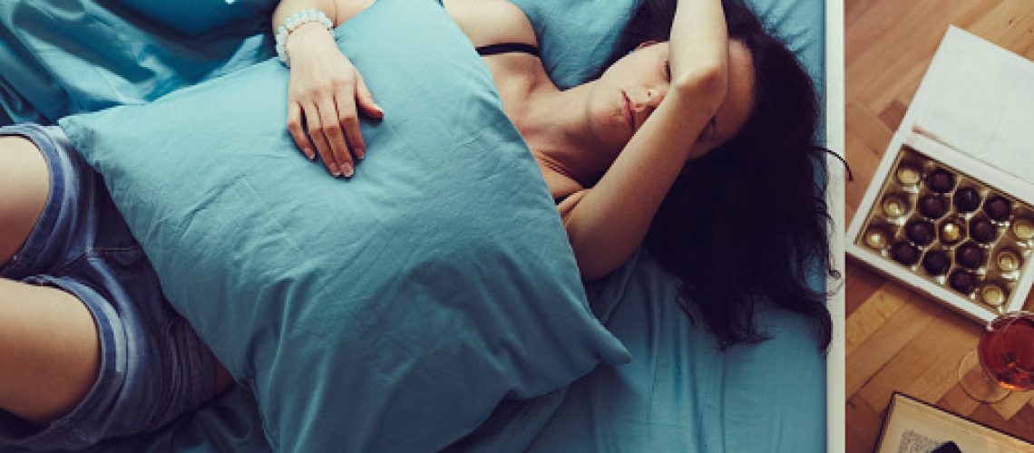 Depressed woman in bed with hand on forehead